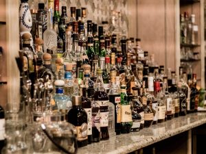 „Vielseitige Auswahl internationaler Spirituosenflaschen auf einem beleuchteten Regal in einer Bar.“