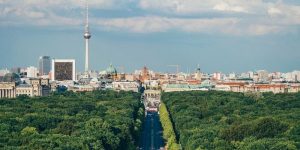 „Panorama-Blick über den Berliner Tiergarten auf die Skyline mit dem Fernsehturm und dem Reichstagsgebäude bei Tageslicht.“